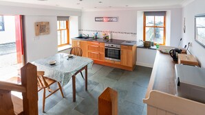 A modern kitchen with a dining area, featuring a granite countertop, wooden cabinets, and a built-in oven.