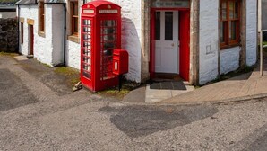 A white building with a red telephone booth and a chimney.