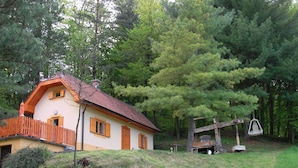 A house with a wooden fence, a swing set, and a bird feeder. - Holiday house for rent in the vineyards (Ptuj)