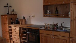 A kitchen with wooden cabinets, a stove, and a sink. - Holiday house for rent in the vineyards (Ptuj)