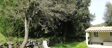 A house with a tiled roof, a stone wall, and two lawn chairs.