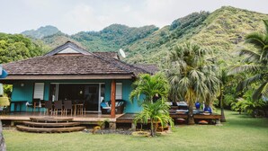 A house with a tiled roof, a porch with chairs, and a view of a green hill.