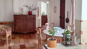 Ein gemütlicher Essbereich mit einem Holztisch, Stühlen und einer Zimmerpflanze. Außerdem ist ein Schrank und eine Pendelleuchte zu sehen.