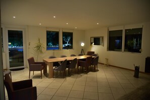 A dining area with a long table and chairs, a potted plant, and a lamp. - Villa Parenthèse, holiday home with swimming pool (Saint-André-de-Cubzac)