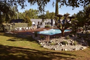A modern outdoor pool area with a stone deck, surrounded by a well-maintained lawn and a small tree. - Villa Parenthèse, holiday home with swimming pool (Saint-André-de-Cubzac)