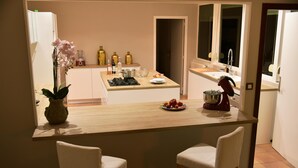 Een keuken met een houten aanrecht, twee witte stoelen, een potorkidee en diverse keukenapparaten.