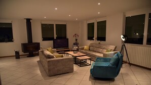 Een moderne woonkamer met een zithoek, een salontafel, een televisie en een vloerlamp.