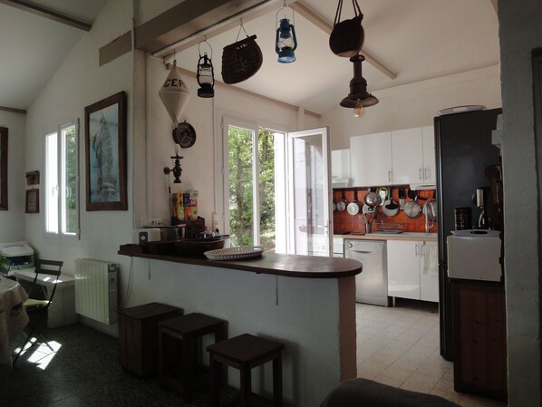A kitchen with white cabinets, a wooden countertop, and hanging lights. There is a window providing natural light.