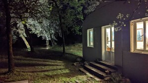 Ein dunkles Haus mit einer kleinen Veranda und Stufen, die zu einer Tür führen.