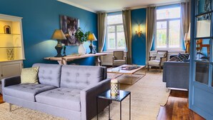 Ein Wohnzimmer mit grauem Sofa, einem Holztisch und einer blauen Wand.