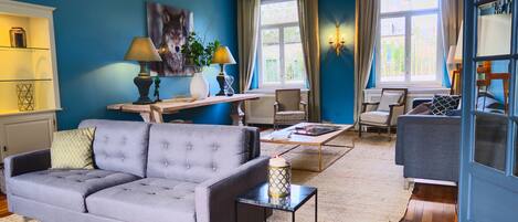 Un salon avec un canapé gris, une table basse en bois et un mur bleu.