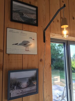 A wooden wall with framed pictures, including a seagull illustration and a beach scene.