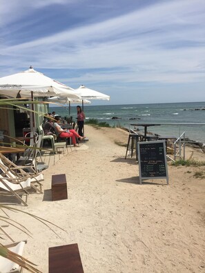 A beachside café with outdoor seating and a chalkboard menu.