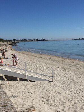 A sandy beach with a few people and a lifeguard tower in the distance.