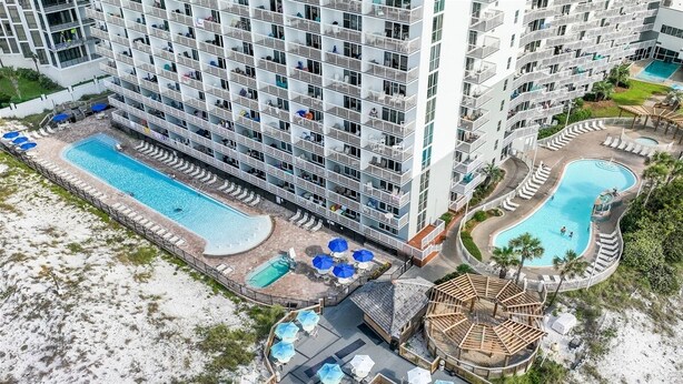 A high-rise hotel with multiple balconies, a central pool, and a separate pool area.
