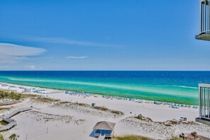 A beach view with a clear sky, a sandy beach, and a small building structure. - Unobstructed Ocean View ,2 bedroom , 12th Floor Pelican Beachfront  (destin)