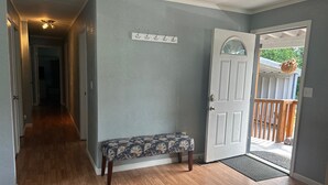 A hallway with wooden flooring, a bench, a door with a glass panel, and a coat rack. - Black Gold Getaway .....Walking distance to town (Valdez)