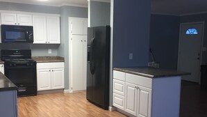 A kitchen with white cabinets, a black refrigerator, a microwave, and a stove. - Black Gold Getaway .....Walking distance to town (Valdez)