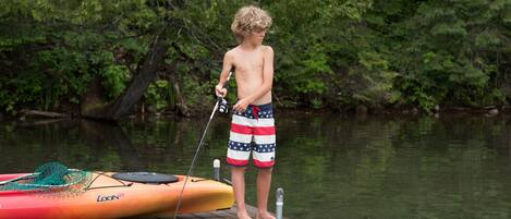 A wooden dock with a kayak and fishing rod.