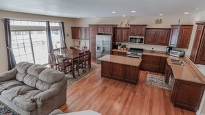 Eine geräumige Küche mit Holzausstattung, einem Edelstahlkühlschrank und einem Essbereich mit grauem Sofa und Holztisch.
