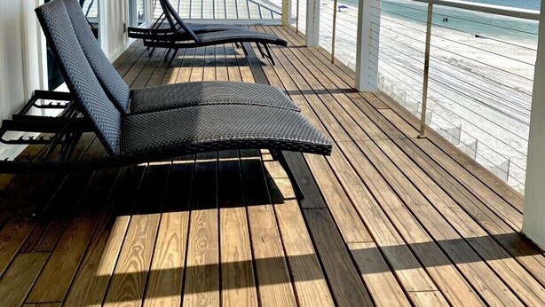 A covered wooden deck with two lounge chairs, a ceiling fan, and a view of the beach. - Gulf front home on North Cape, outdoor kitchen, elevator @ lots of beach gear (Port St Joe)