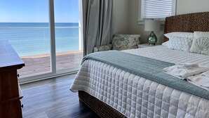 A bedroom with a bed, a nightstand, a lamp, and a view of the ocean. - Gulf front home on North Cape, outdoor kitchen, elevator @ lots of beach gear (Port St Joe)
