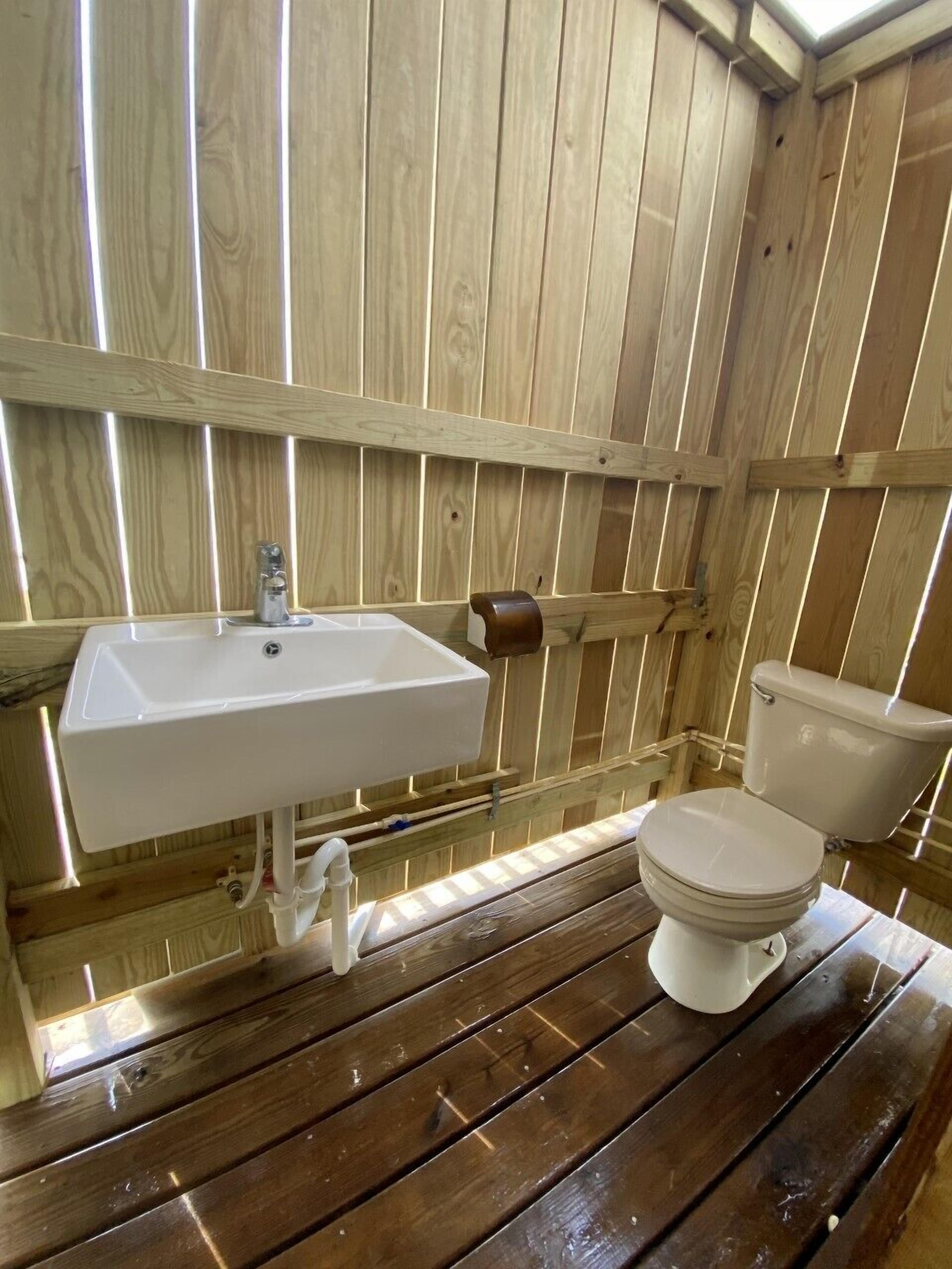 A wooden interior with a white sink and toilet.
