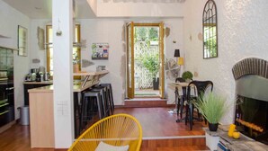 A spacious living area with a wooden floor, a yellow wicker chair, a fireplace, and a kitchen area visible through an open doorway. - In the heart of the old town, quiet loft with pretty sunny terrace (Annecy)