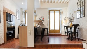 A modern kitchen with built-in appliances, a dining area with a table and chairs, and a wooden floor. - In the heart of the old town, quiet loft with pretty sunny terrace (Annecy)