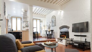 A modern living room with a fireplace, a flat-screen TV, and a dining area with a table and chairs. - In the heart of the old town, quiet loft with pretty sunny terrace (Annecy)
