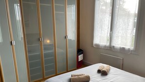 Ein Schlafzimmer mit Bett, Schrank, Fenster und Heizkörper.