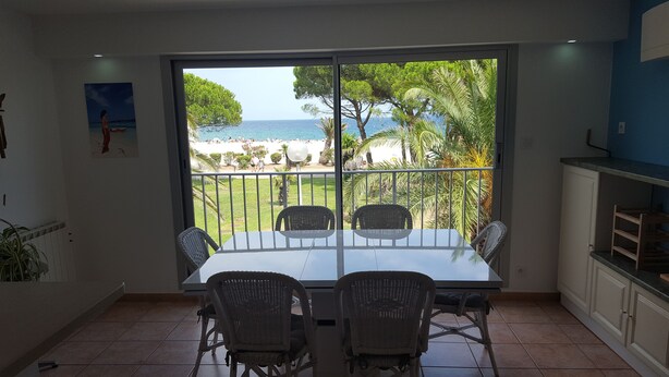A dining area with a view of the beach, wicker chairs, a glass table, and a white cabinet. - Exceptional sea view, seafront, Argeles Plage, Climatisation, Large apartment (Argelès-Sur-Mer)