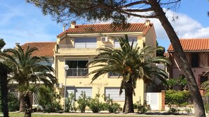 A two-story building with a red-tiled roof, surrounded by palm trees and cacti. - Exceptional sea view, seafront, Argeles Plage, Climatisation, Large apartment (Argelès-Sur-Mer)