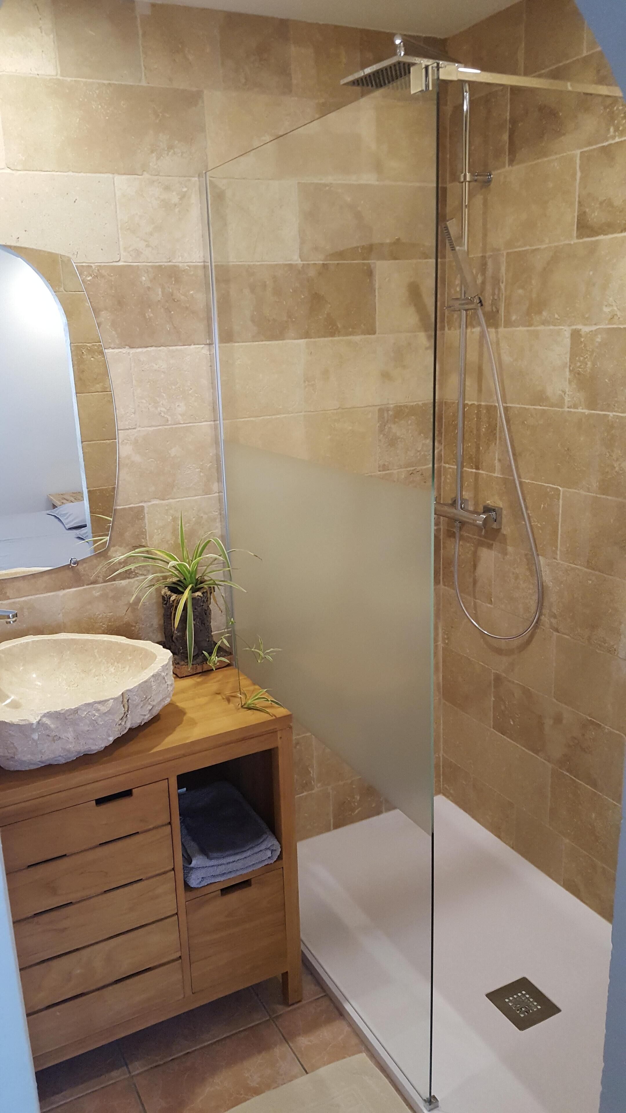 A bathroom with a glass-enclosed shower, a round sink, and a wooden vanity.
