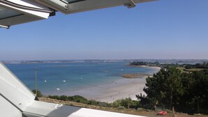 A coastal view from a window, including a beach and distant shoreline.