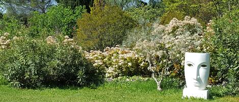 A garden with various plants and a white sculpture.