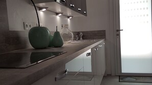 A modern kitchen with a dark countertop, a glass pitcher, and a green bowl.