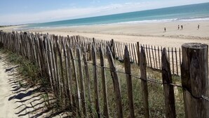 Een strand met een houten hek op de voorgrond en een helder uitzicht op de oceaan.