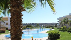 A pool area with a fountain, surrounded by palm trees and a well-maintained lawn. - Superb Albufeira apartment in the Algarve (la Marina Albufeira)