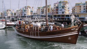 A traditional wooden boat named LEAOZINHO docked at a marina with colorful buildings in the background. - Superb Albufeira apartment in the Algarve (la Marina Albufeira)