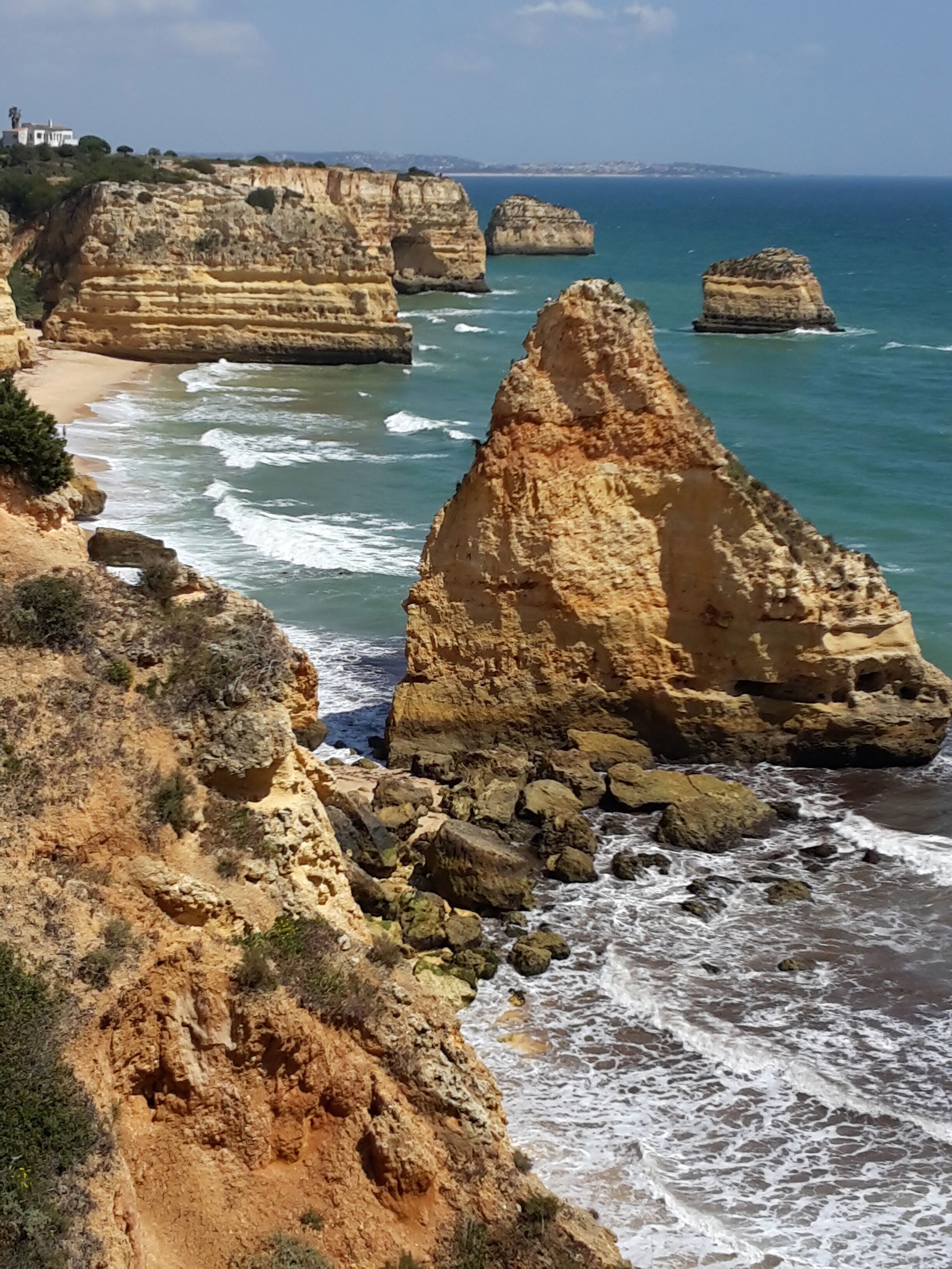 Un paysage côtier caractérisé par des formations rocheuses imposantes et une plage.