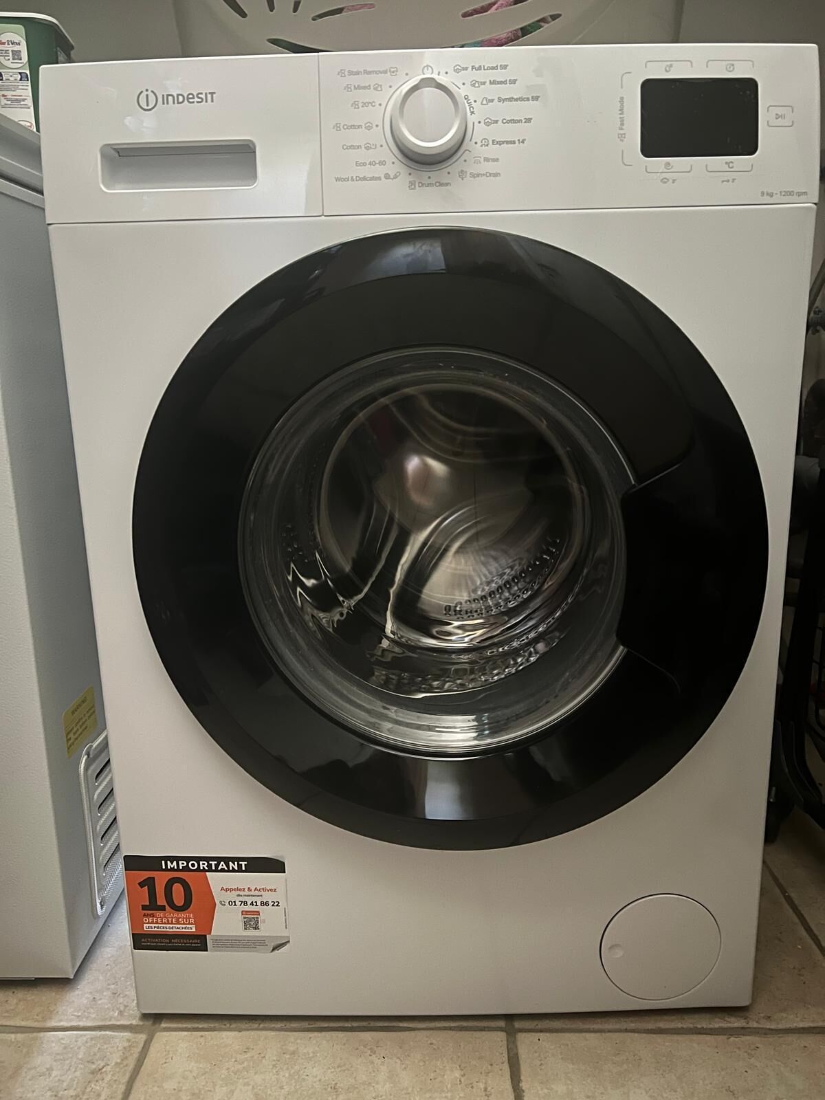 A front view of a white washing machine with a control panel, a digital display, and a prominent dial.