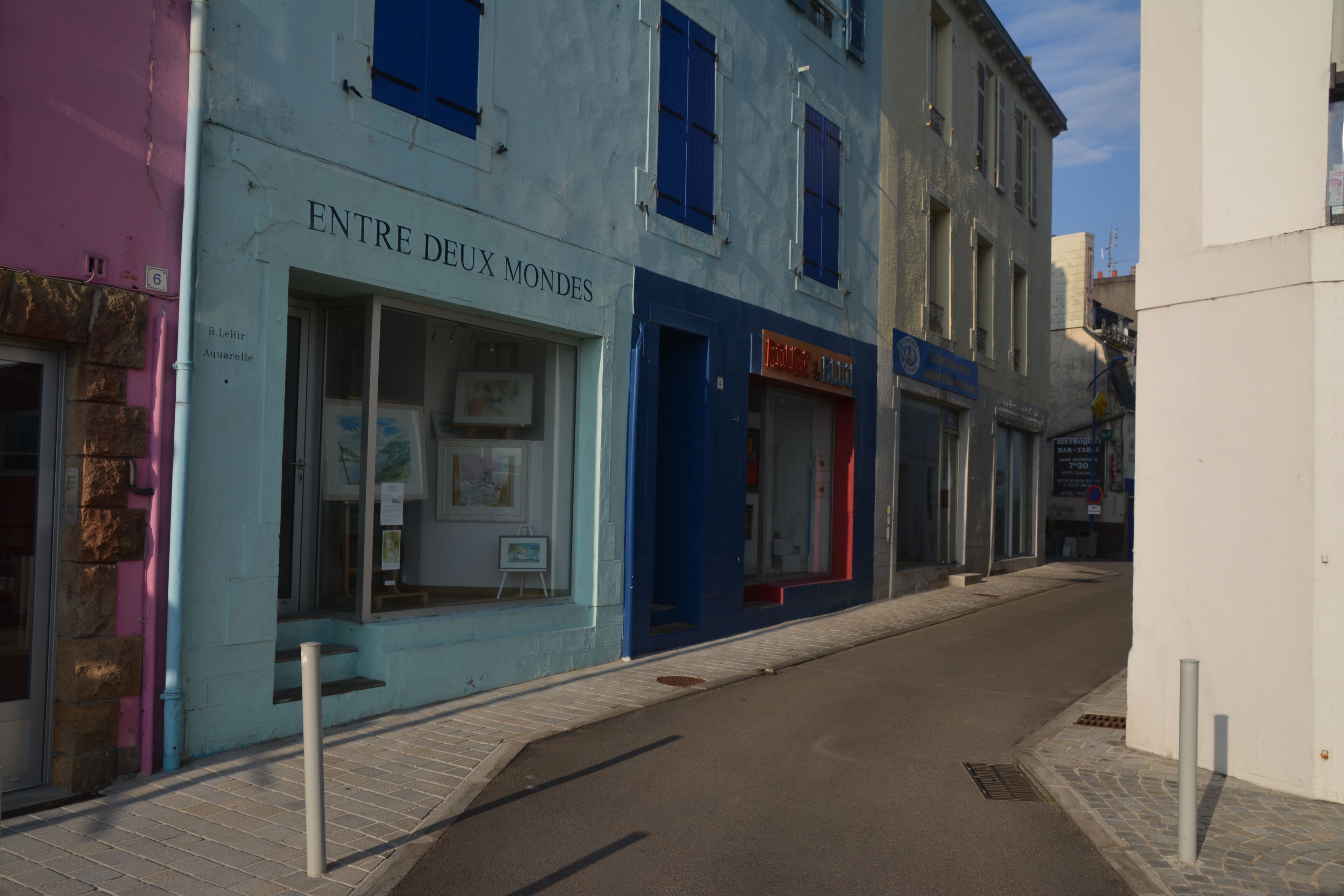 A street with buildings, one of which has a sign reading "Entre Deux Mondes".