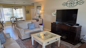 A living room with a sofa, coffee table, TV, and decorative items. - 4 BEDROOM HOUSE JUST A WALK TO THE BEACH! (Indian Harbour Beach)