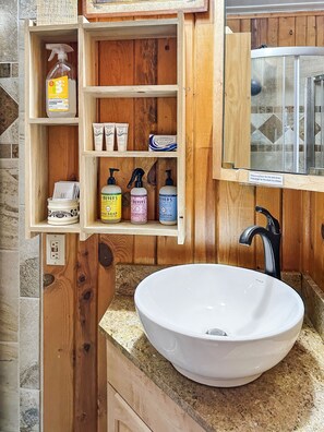 A wooden bathroom with a white sink, shelves with toiletries, and a window with a sink drain instruction. - Lemmon Lodge - Private Beachfront and Fishing! (Grand Lake)