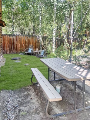 A picnic table and bench in a backyard with a wooden fence and greenery. - Lemmon Lodge - Private Beachfront and Fishing! (Grand Lake)
