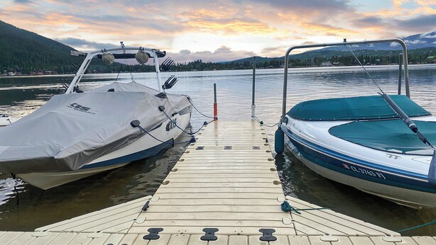 A wooden dock with two boats moored at the end.