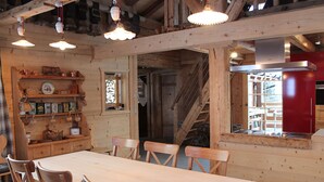 Ein Holzinnenraum mit einem Esstisch, Stühlen, einer Treppe und einem roten Gerät.