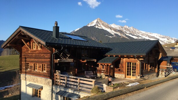 Eine Holzhütte mit Steinunterbau, großen Fenstern und einer Veranda.