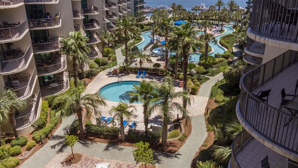 Een resort met meerdere zwembaden, palmbomen en uitzicht op de oceaan.